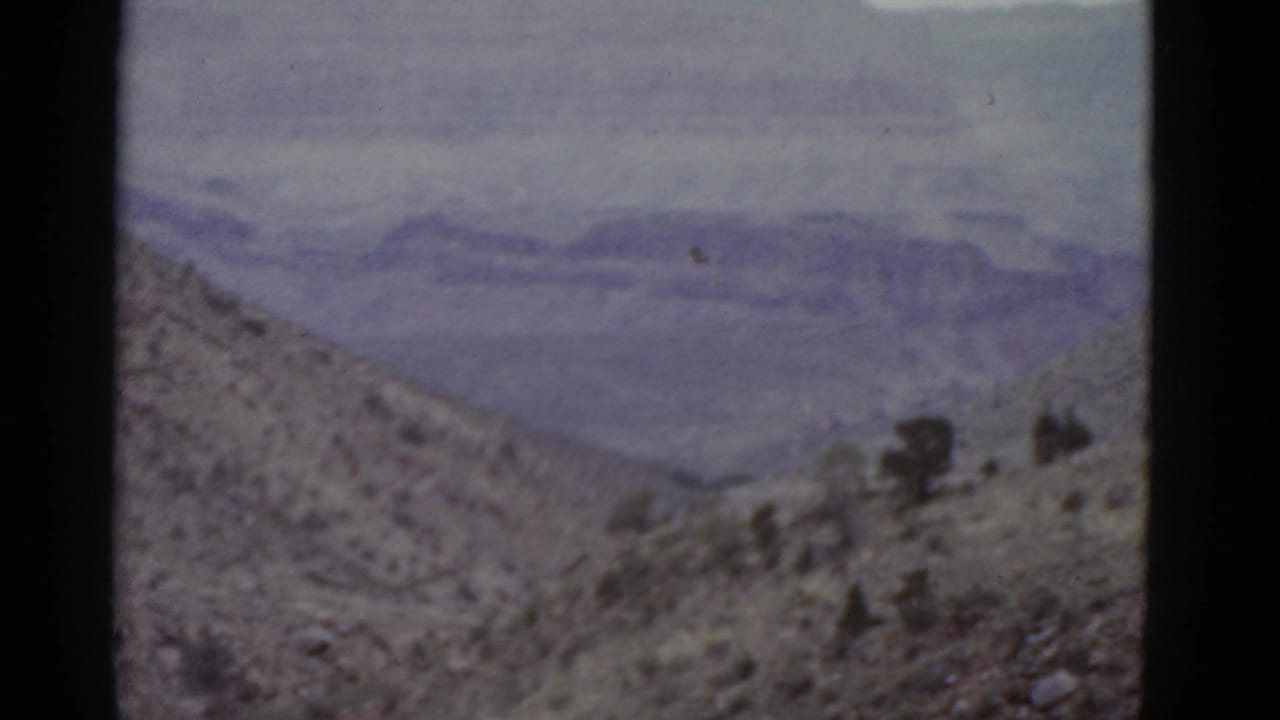Desert slope and distant mountain range framed by dark film edges.