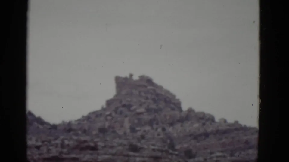 1952 Arizona 8mm frame featuring a rugged desert rock outcrop against a washed, pale sky.