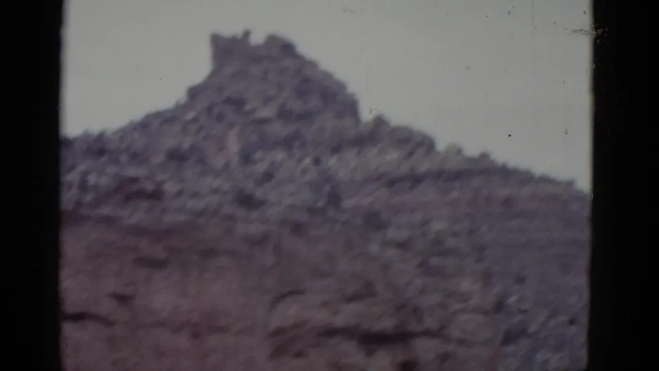 1952 Arizona 8mm frame with a closer view of a rough mesa ridge, horizontal rock layers, muted color, and film edge borders.