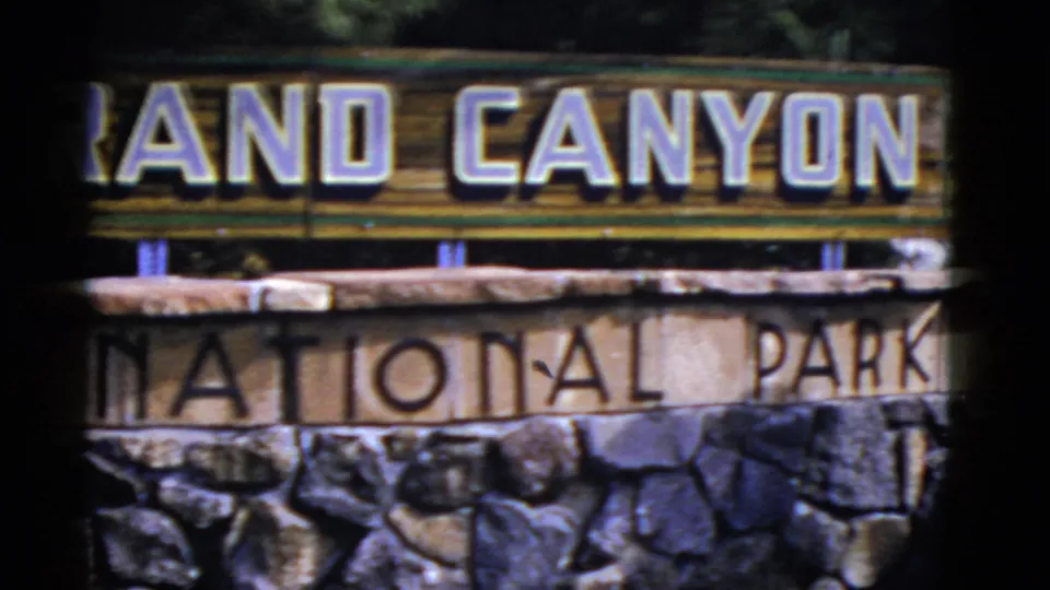 1952 Arizona home-movie frame showing cropped Grand Canyon lettering above National Park text and a rough stone base.