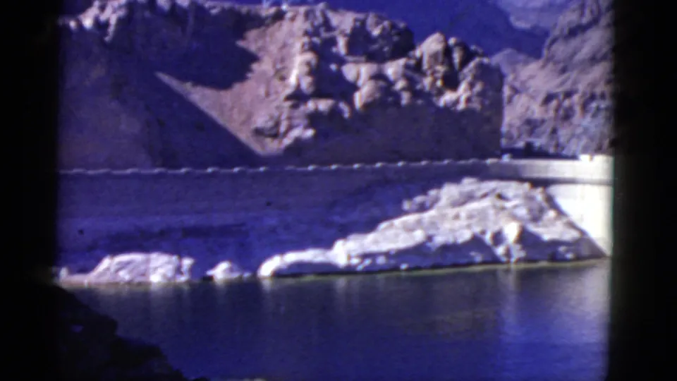 Scenic 1952 California home-movie view of reservoir water, pale rocks, mountain slopes, and a dam structure.