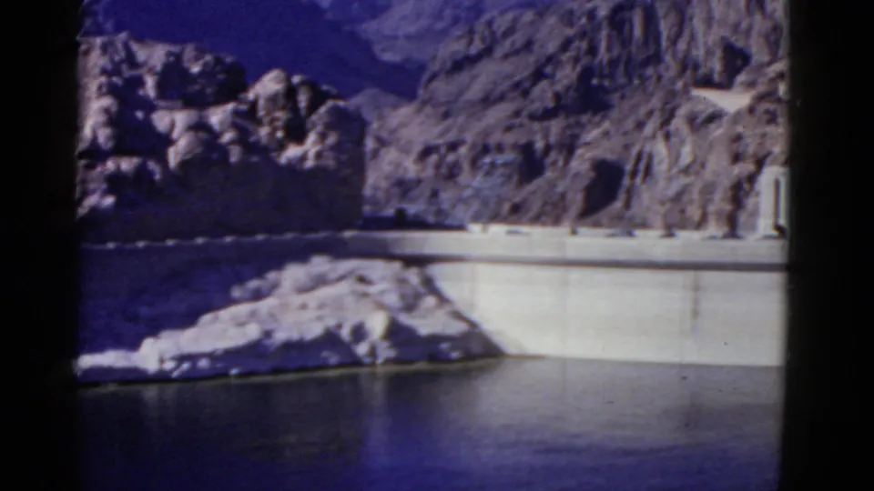 The California dam and reservoir remain centered as the 1952 8mm camera pans across the rocky landscape.
