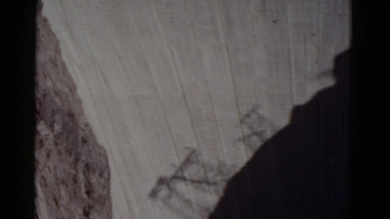High-angle view of a concrete dam face beside a steep canyon wall.