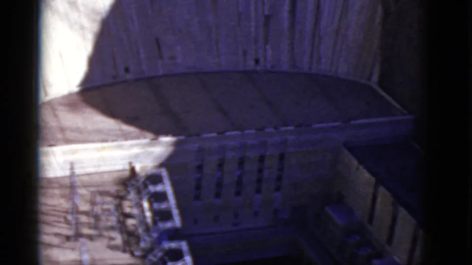 High-angle 1952 home-movie view of Hoover Dam's lower concrete details, canyon surfaces, and deep shadow.
