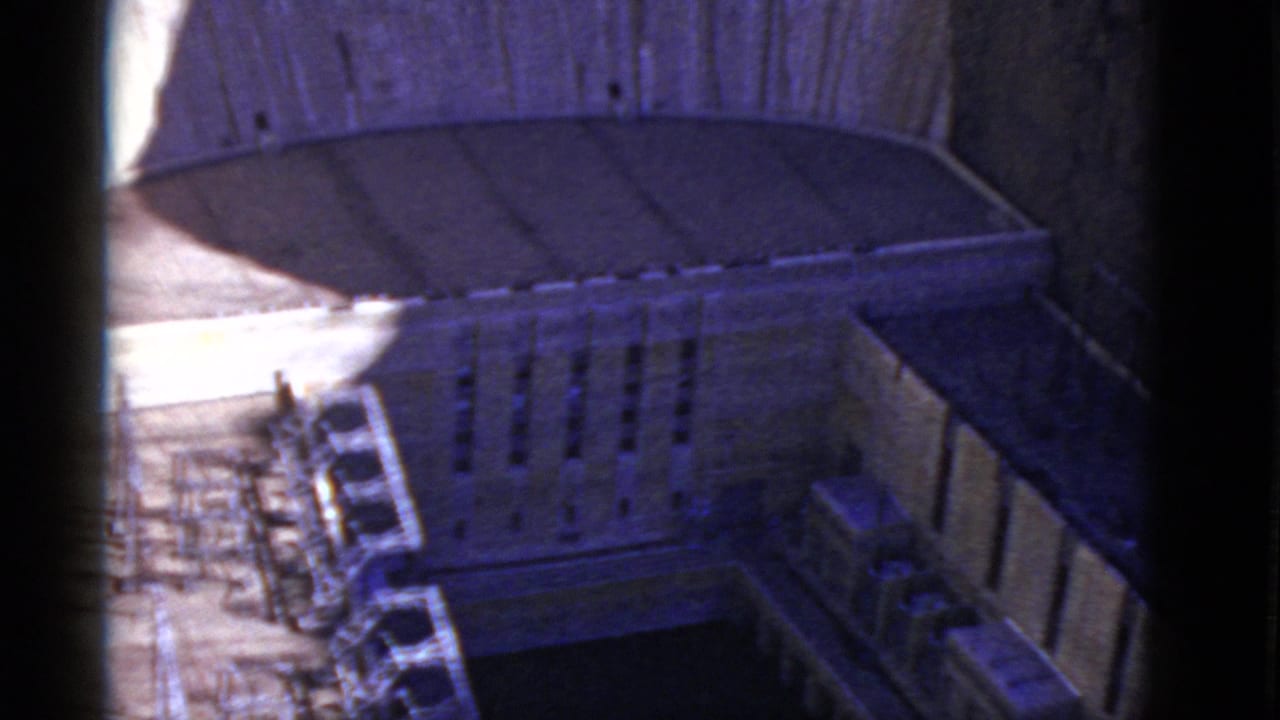 High-angle view of a stone institutional courtyard with parked cars and a curved roofline.