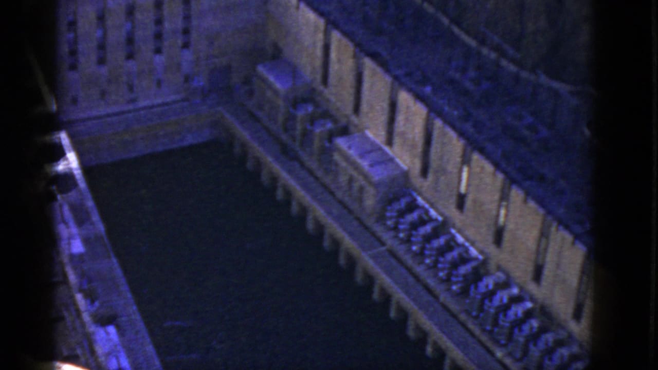 Elevated view of a concrete industrial structure beside a dark water channel.
