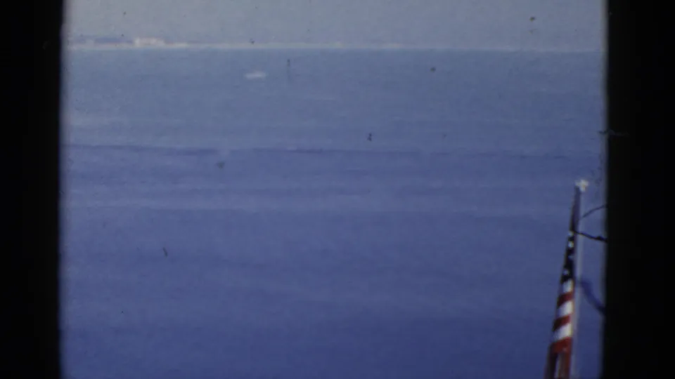 1952 California 8mm frame with the flag partly cropped at right and a broad sea horizon in view.