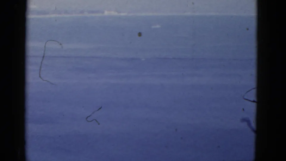1952 California 8mm frame dominated by open sea, pale sky, and dark film borders, with the flag largely absent.