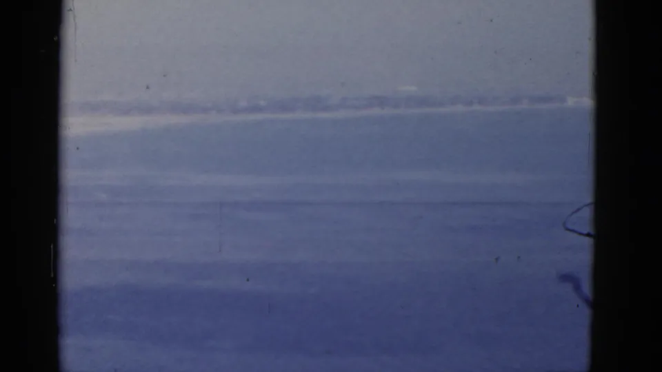 1952 California 8mm frame showing a calm sea horizon, pale sky, and a partial flagpole along the right edge.