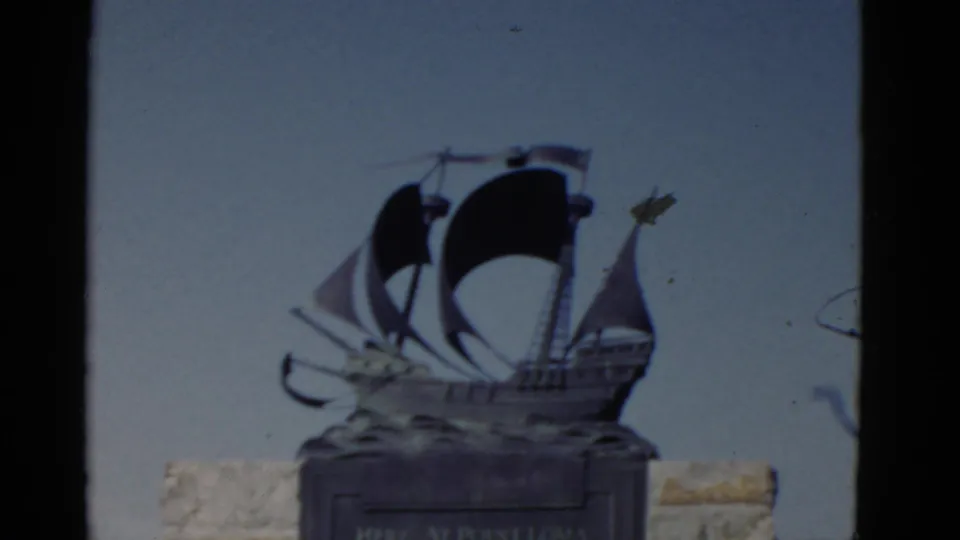 Point Loma monument detail from 1952 home-movie footage, showing a ship sculpture with dark sails on a stone base.