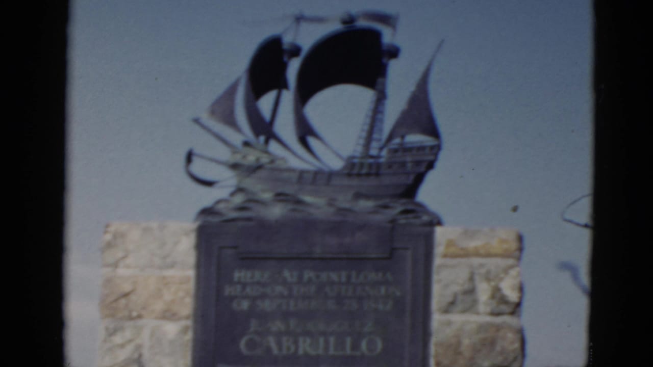 1952 California home-movie frame showing the Cabrillo monument plaque and bronze ship sculpture at Point Loma.