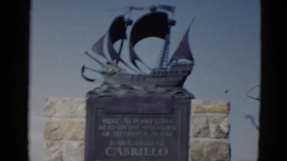 1952 California home-movie frame showing the Cabrillo monument plaque and bronze ship sculpture at Point Loma.