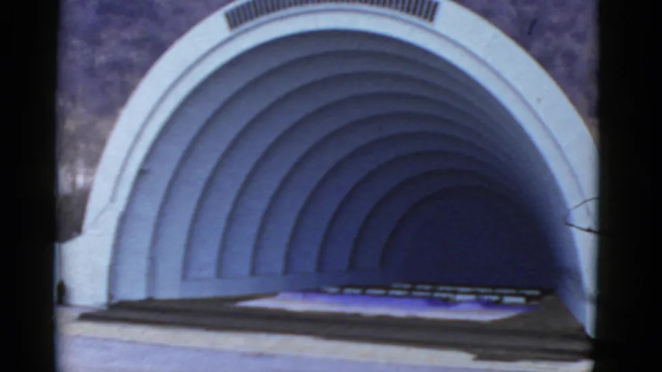 1952 California home-movie frame of a white outdoor bandshell, seen closer with curved ribs and an empty stage.