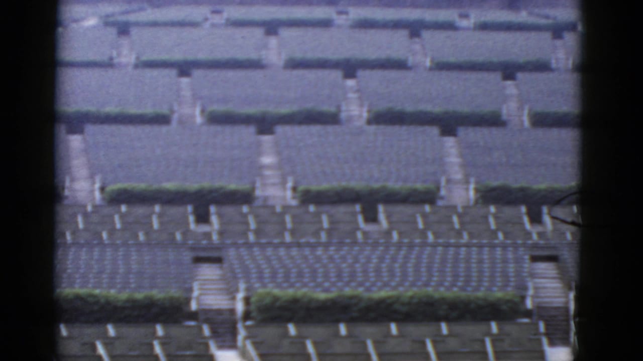 Distant rows of gray bungalow roofs divided by paths and green hedges.