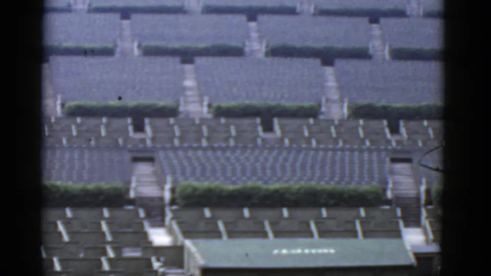 Distant California housing development view with patterned bungalow rows, hedges, walkways, and part of a green-roofed structure.