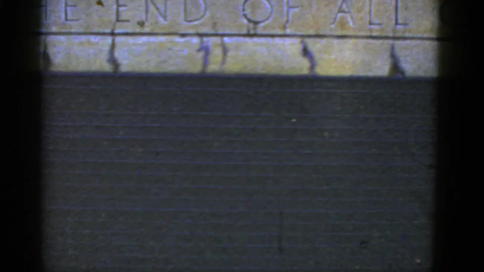 Close 1952 California 8mm view of carved lettering that appears to read part of “THE END OF ALL” above a dark wall.