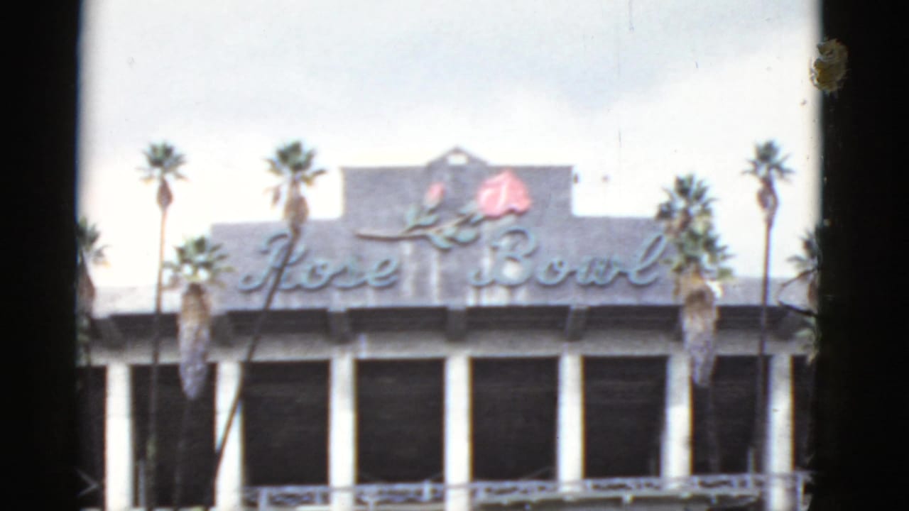 Rose Bowl sign on a building facade with palm trees and white columns.