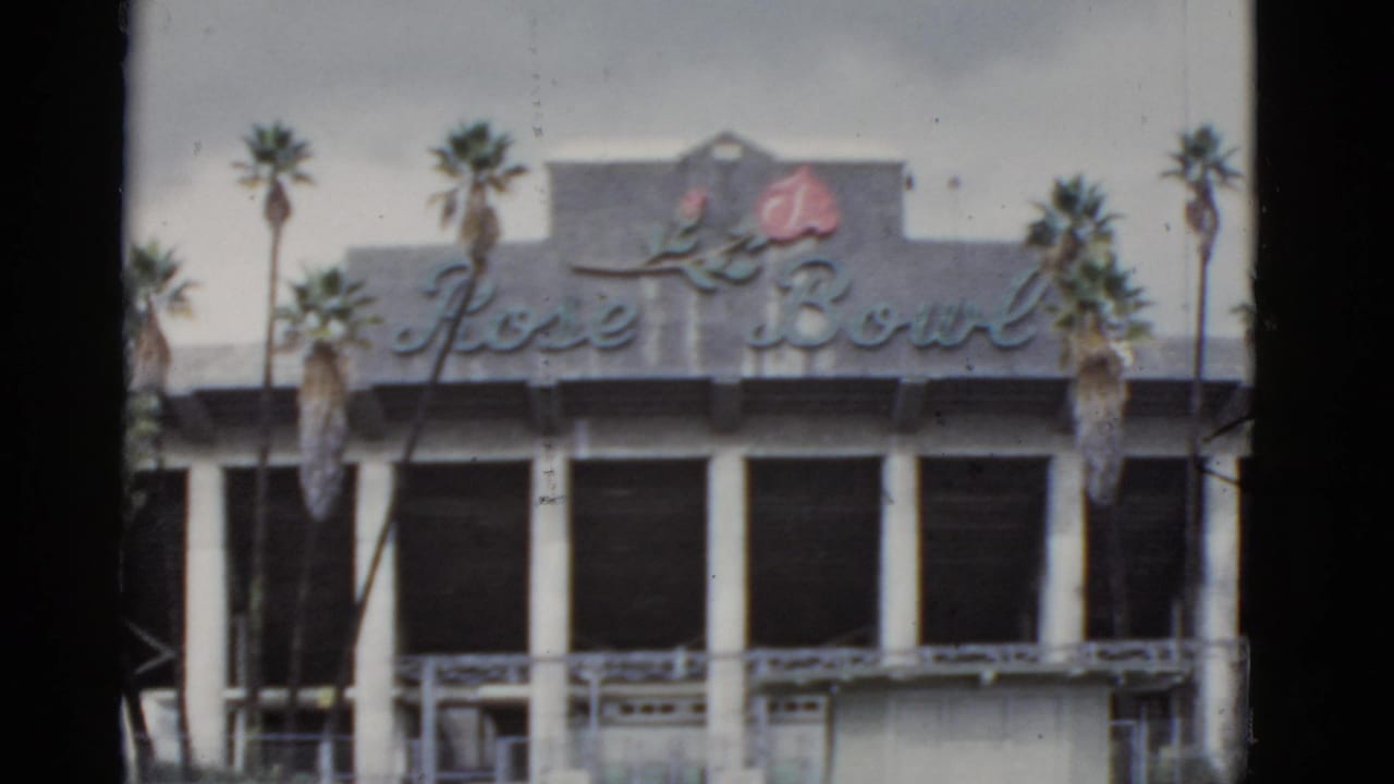 Rose Bowl facade with cursive sign, rose emblem, columns, and palm trees.