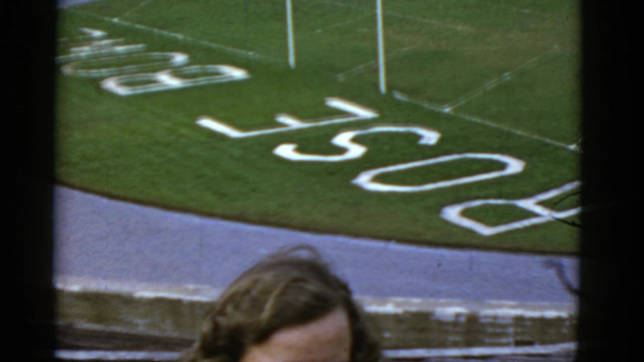 Top of a woman's head appears below a football field with white PACIFIC lettering and yard markings.