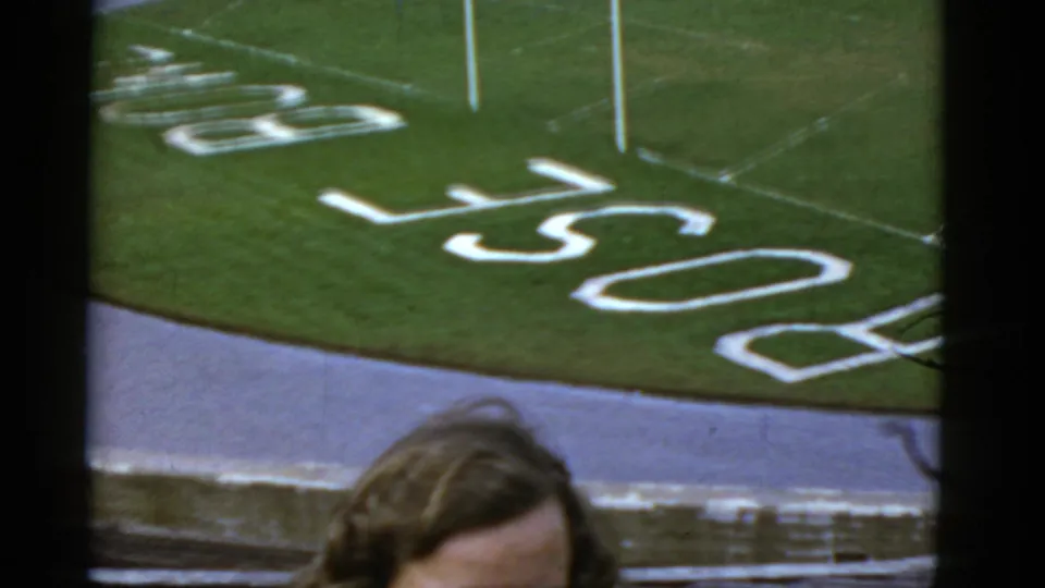 The camera frames the football turf and PACIFIC lettering while the woman is partly visible at the bottom edge.