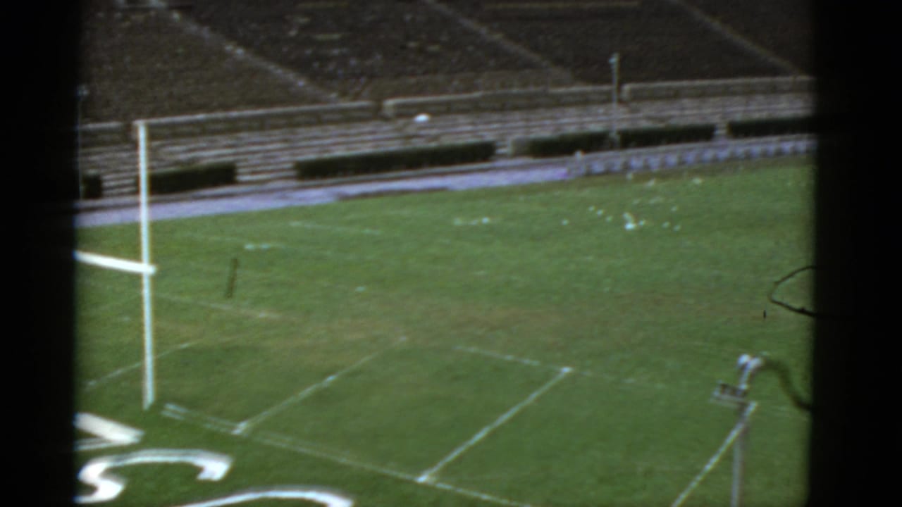 High view of an empty football field with a goalpost, yard lines, and bleachers.