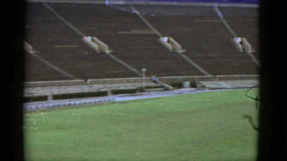 High-angle 8mm view of a California football stadium in 1952, showing green turf below empty concrete seating.
