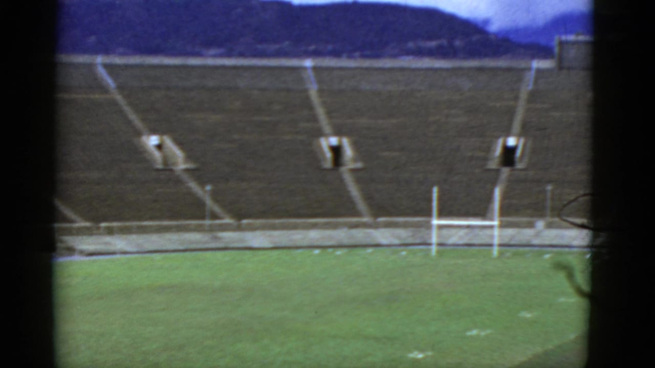 Stadium field and tiered seats framed by dark vertical film borders.