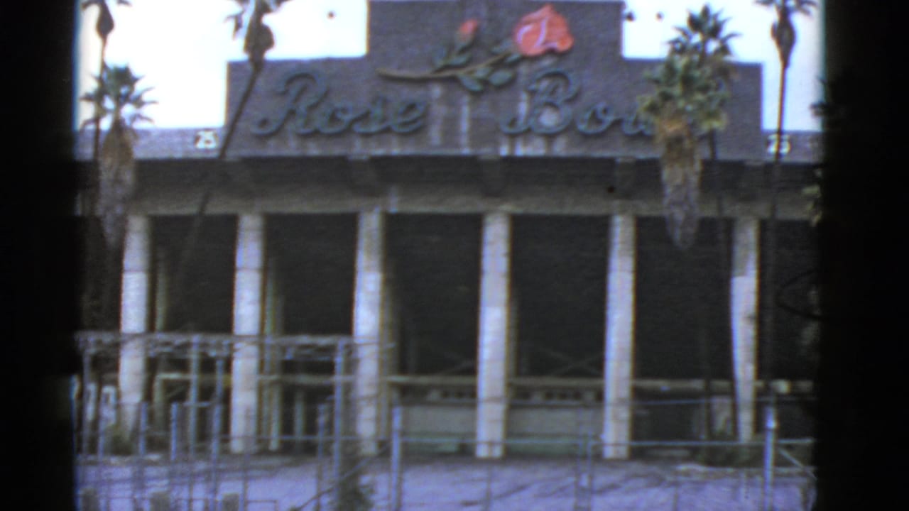 Faded Rose Bowl sign above a worn building facade with columns and palm trees.