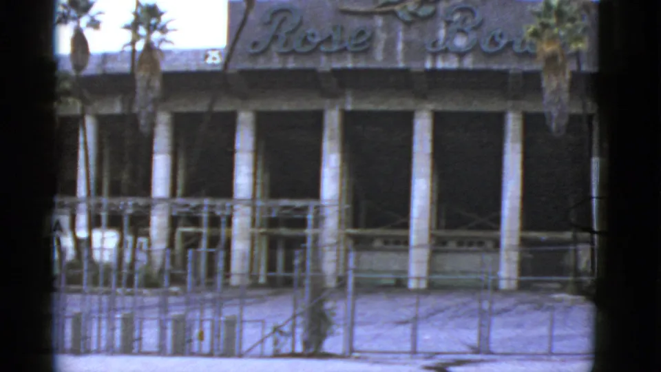 1952 California frame with Rose Bowl lettering over a closed-looking facade, palm trunks, scaffolding, fence lines, and dark windows.