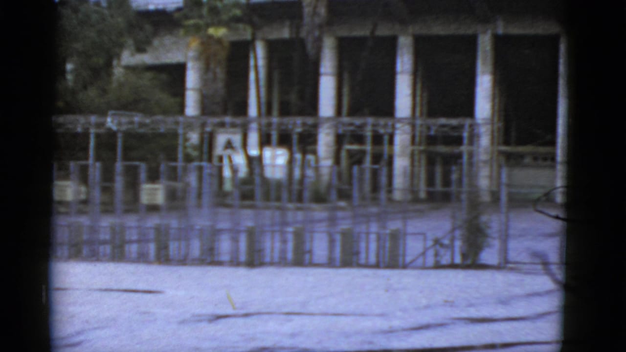 Metal gate and fenced enclosure in front of a columned building.