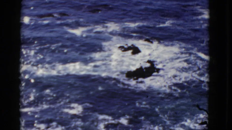 Blue Pacific surf breaks around dark rocks in this 1952 San Francisco coastal home-movie frame.