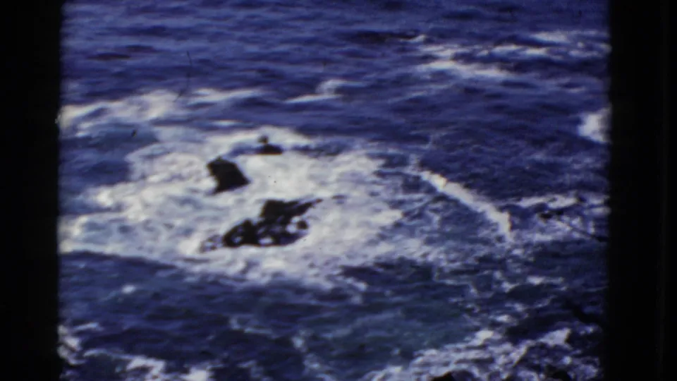 1952 San Francisco home-movie view of churning blue surf and white foam around jagged dark rocks.