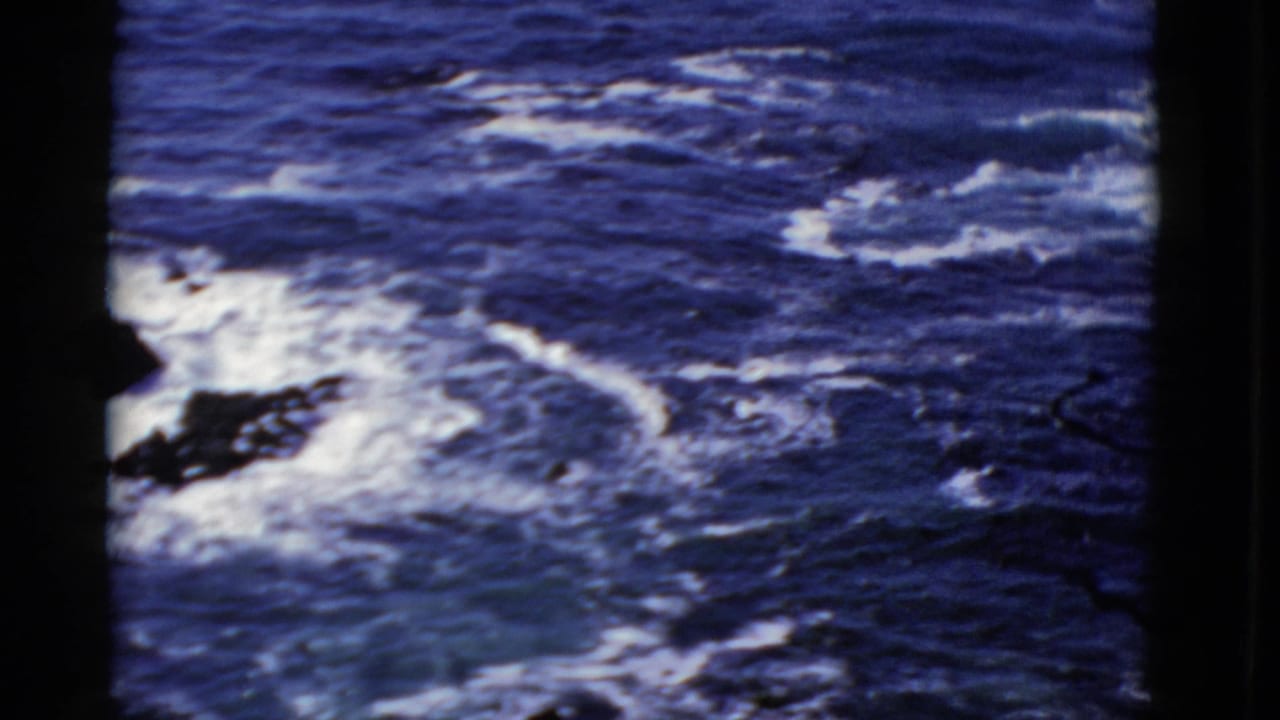 Color 8mm view of turbulent Pacific surf near San Francisco, framed by black gate edges and visible film marks.