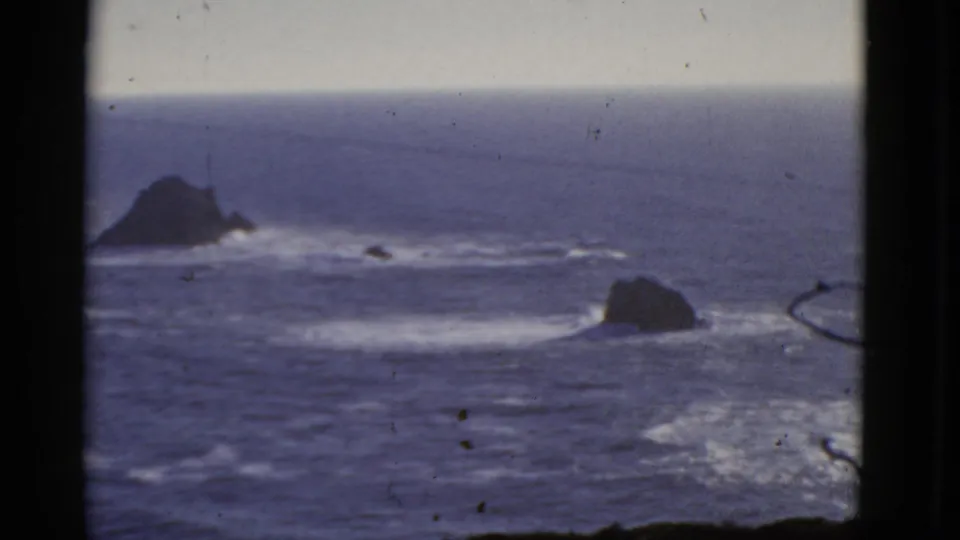 Wide 8mm coastal view from San Francisco showing blue water, scattered offshore rocks, and white surf bands.