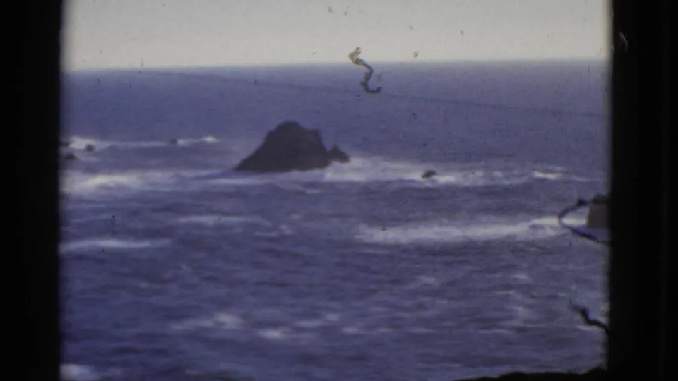 A San Francisco 1952 home-movie frame shows turbulent blue ocean, offshore rocks, pale horizon, and visible film wear.