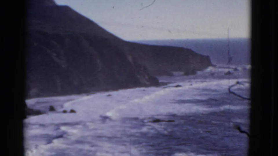 Vintage 8mm view of a rugged San Francisco shoreline, with cliffs, breaking waves, and soft blue water tones.
