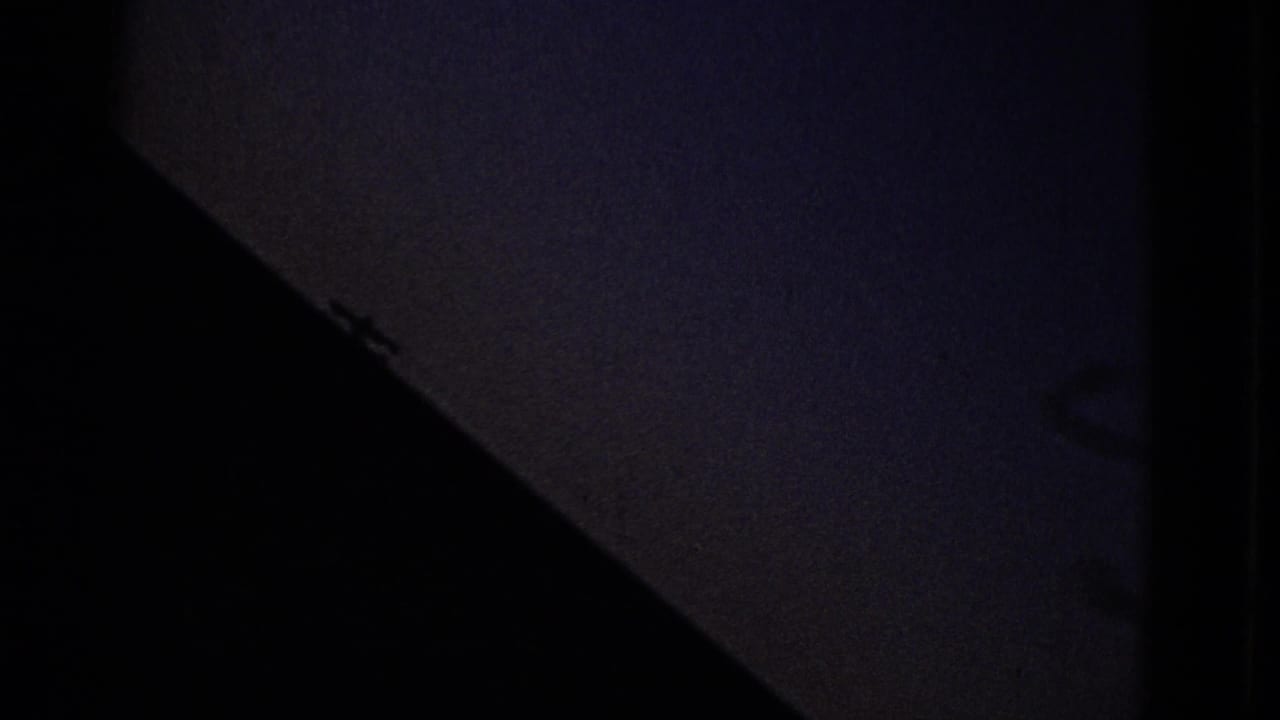 Dark triangular foreground shape against a dim blue sky.