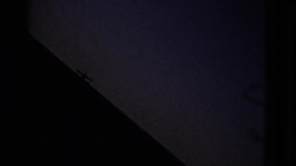 Dim 8mm frame with a dark triangular foreground silhouette and dusky blue sky, likely part of the same San Francisco Bay home-movie sequence.