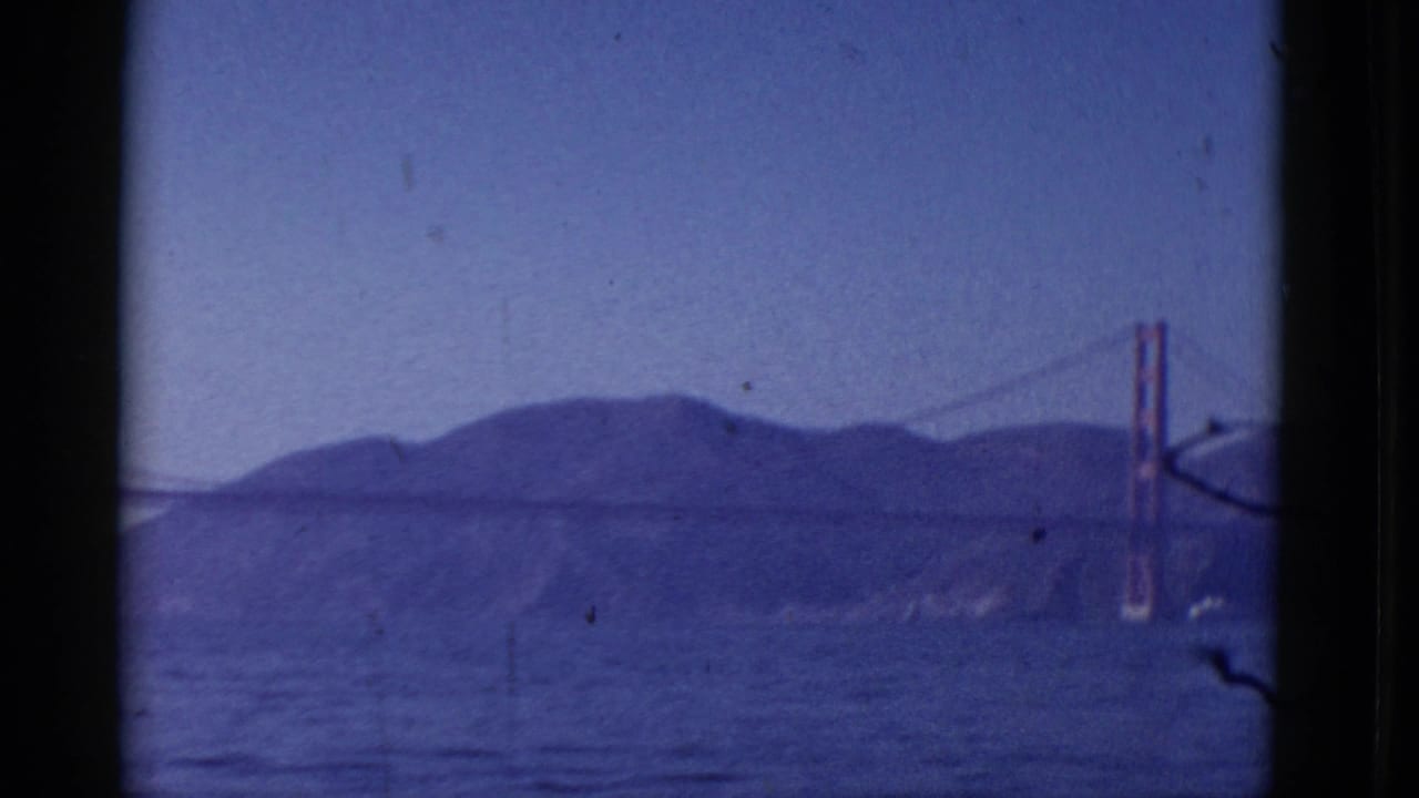 1952 8mm view of the Golden Gate Bridge seen across San Francisco Bay, with hills, haze and dark window-like frame edges.