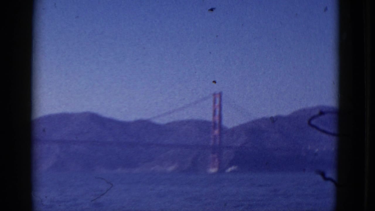 Golden Gate Bridge in soft focus beyond water, hills and dark vertical frame edges.