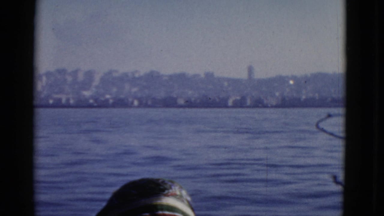 1952 San Francisco skyline seen across the water from a visitor viewpoint, with dark frame edges and a partial head in the foreground.