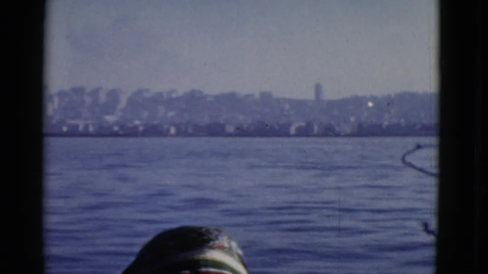 1952 San Francisco skyline seen across the water from a visitor viewpoint, with dark frame edges and a partial head in the foreground.