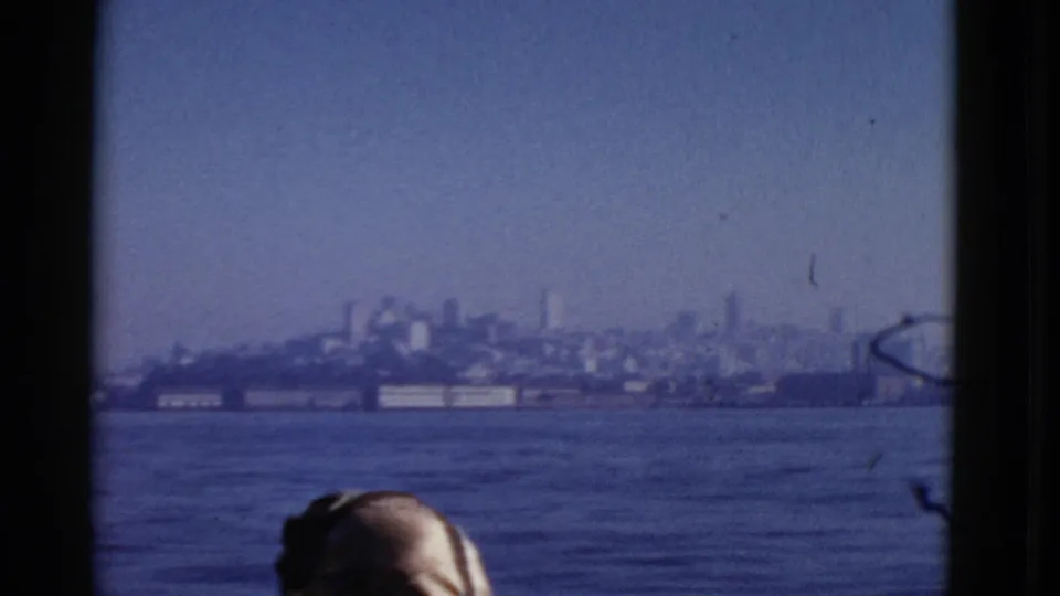 Hazy San Francisco shoreline across the bay, framed by the boat with a passenger's head partly visible at the bottom.