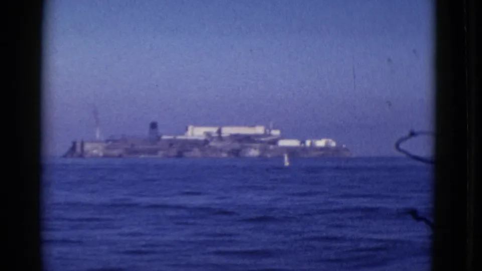 Distant 1952 San Francisco Bay view of Alcatraz Island, filmed from shore or a boat with open water in the foreground.