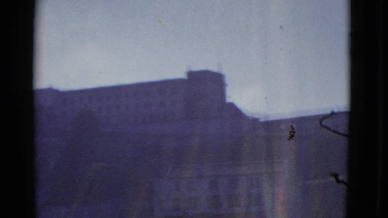 Large flat-roofed building silhouette with window-edge shadows and pale sky.
