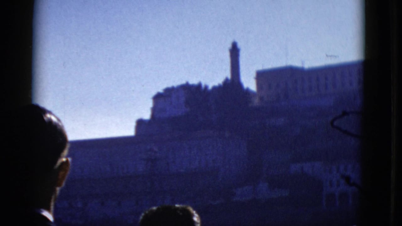 1952 San Francisco 8mm frame showing dark passenger silhouettes and Alcatraz Island across the bay.