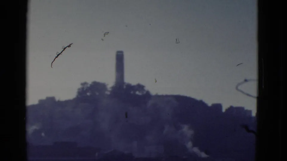 1952 San Francisco frame with a tower above a dark hillside and pale smoke or mist rising near the lower slope.