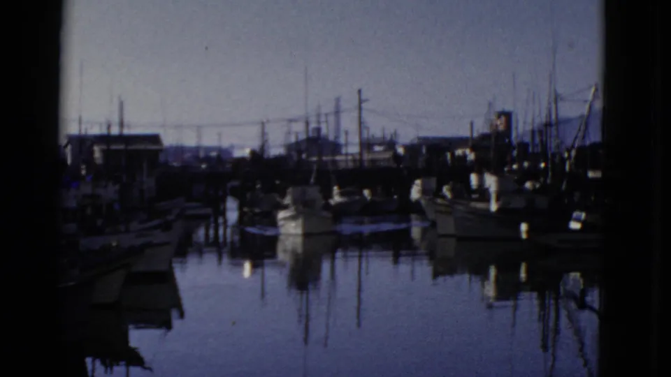 San Francisco harbor view from 1952 home-movie footage, showing docked boats, tall masts, piers, and reflections in still water.