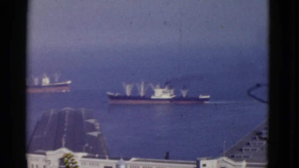 Elevated 1952 San Francisco harbor view showing two cargo vessels moving across blue water near foreground pier structures.