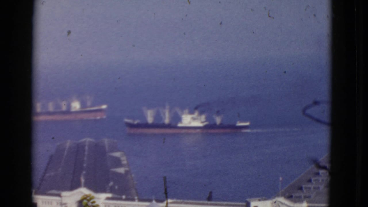 1952 San Francisco Bay home-movie frame showing two ships on blue water, seen from an elevated view with rooftops below.